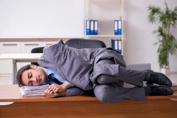 Young male employee sleeping in the office