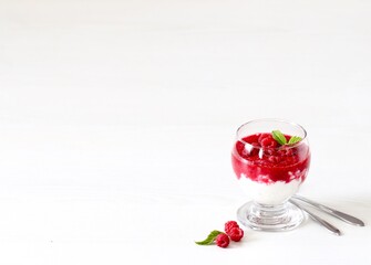 Cottage cheese cream berry dessert with fresh raspberries in a glass on a white background copy space