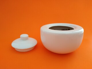 
beautiful white sugar bowl with an orange background