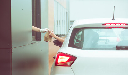 Employee wearing gloves delivers take out food out the window. Shopping for food from the car. Pick...
