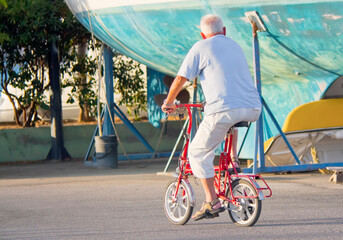  Elderly man riding a mini bicycle 