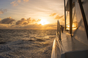 vista lateral de barco a motor navegando em alto mar durante por do sol