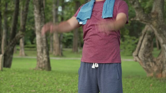 Asian man swing his arms  doing standing exercise warming up at the park, elder low impact work out arms full stretch, health care, mid body section, easy simple basic exercise for beginner, diet plan