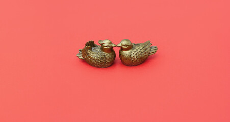 Mandarin ducks statuettes on red background. Symbol of love and loyalty in feng shui. Selective focus. Banner, copy space