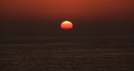 Sun disappearing below horizon at sunset on the ocean