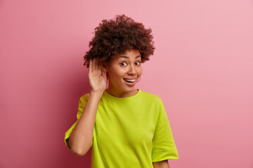 What you say? Positive ethnic woman keeps hand near ear to hear gosipping better, eavesdropes...