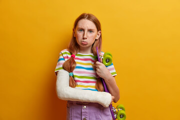 Upset offended girl going to cry, poses with skateboard, wants to have active summer holidays, has...
