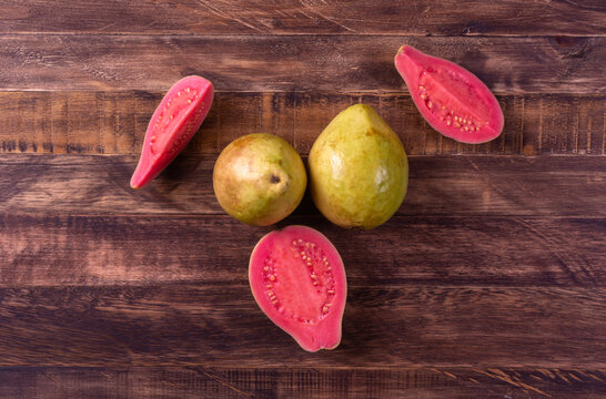 Whole guava fruits and slices over old wood. Top view