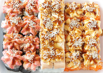 Japanese sushi food. Baked warm rolls with tuna, salmon, shrimp, crab and avocado. Top view of assorted sushi.