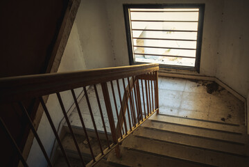 Abandoned staircase of a deserted building with bright light through the window.