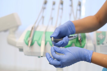 Dentist's hands in Blue gloves working with dendal drill in dental ofice