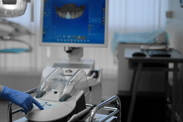 Hand in protective glove pressing buttons on dental hygienic mashine