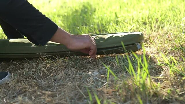 The masked sniper, sharpshooter lays the case of the rifle on the ground, opens it, takes the rifle out of it - Slow Motion