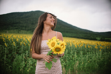 a young beautiful smiling girl poses in a field of sunflowers 