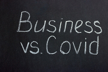 
The inscription on the chalk board "Business versus covid". The slogan of modern reality