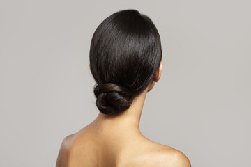 brunette with a smooth bun hairstyle from the back. on gray background