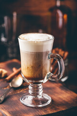 Irish coffee with cinnamon on wooden surface