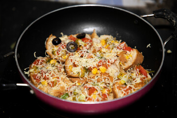 Hot colorful Garlic Bread vegetable cheese pizza with black olives ready to serve in frying pan with vegetables like tomato onion capsicum