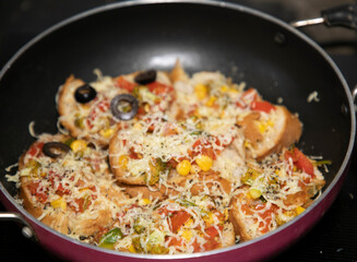 Hot colorful Garlic Bread vegetable cheese pizza with black olives ready to serve in frying pan with vegetables like tomato onion capsicum
