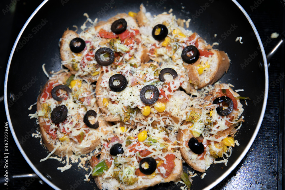 Wall mural Hot colorful Garlic Bread vegetable cheese pizza with black olives ready to serve in frying pan with vegetables like tomato onion capsicum - Wall murals