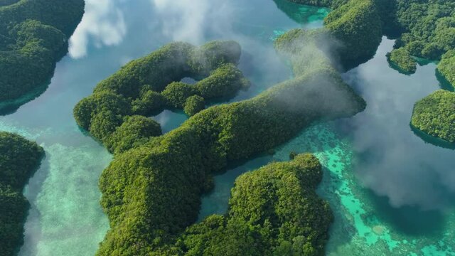 Aerial shot flying over rock islands of Palau with calm reflective water
