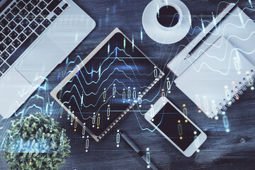 Double exposure of forex chart hologram over desktop with phone. Top view. Mobile trade platform concept.