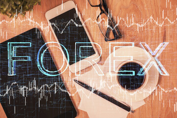 Double exposure of forex chart hologram over desktop with phone. Top view. Mobile trade platform concept.