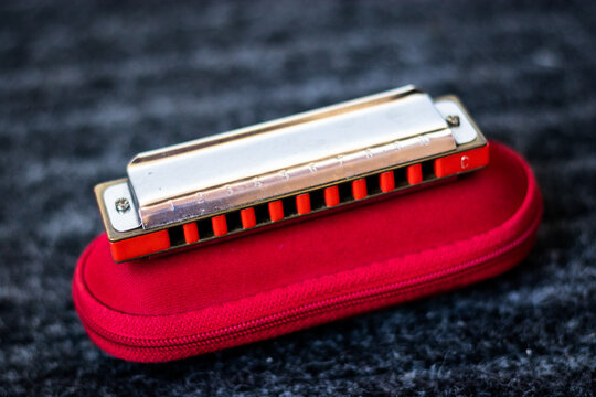 Red Harmonica Music Instrument On Top Of Its Case