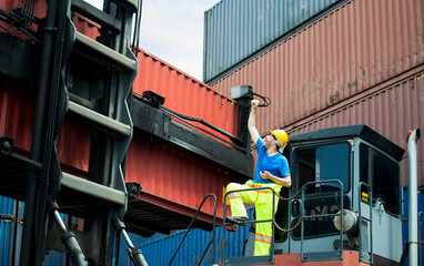 Supervisor engineer in safety helmet raise his hands up for success job at the machine,lifting the container trainer into the storage area. Unload and loading variety of products, successful teamwork 