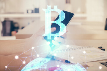 Double exposure of man's hands holding and using a phone and crypto currency blockchain theme drawing.