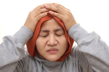 Sad Asian muslim woman wearing hijab crying with regret gesture, hands on head, eyes closed, depression concept