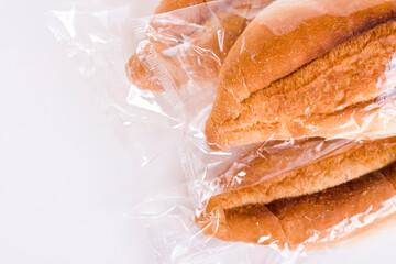 Fresh and crispy breads in transparent nylon bag on the white background with copy space