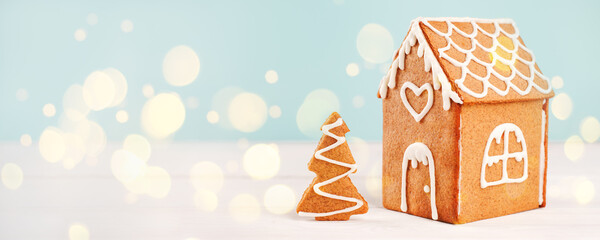 Homemade gingerbread house scene on warm blue bokeh background, Merry Christmas, Happy New Year congratulations banner, copy space, flyer, post card, voucher, coupon