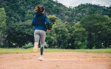 Obraz premium Woman doing workout by running on dirt road (or Trail running). The benefit when running on dirt road can reduce impact on the joints and pushes your muscles in a variety of challenging ways.