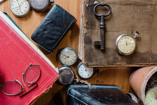 antique accessories and stationery on a wooden table background. antique keys, watch, phone, glasses, pen, compass. nostalgic sentimental picture.