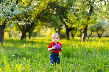 a boy stands in a clearing and plays with a ball