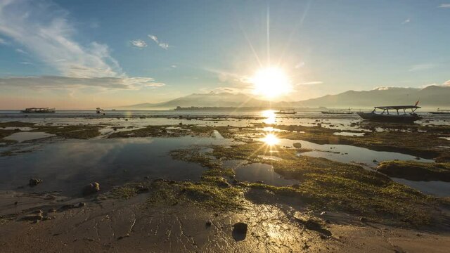 Sunrise in Gili islands. view to lombok. Vulcano Rinjani Bali . Indonesia. Timelapse hyperlapse. 4k video. Fast clouds moving. Gili Air, Gili Meno, Gili Travangan. boats in ocean, low tide beach.