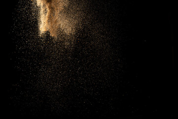 Fototapeta na wymiar Gold sand explosion isolated on black background. Abstract sand cloud.