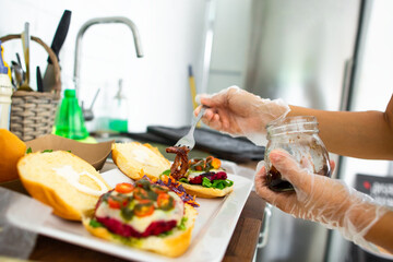 Close up of the hands of a girl chef in gloves сook on the kitchen vegetarian burgers from beets and adds caramelized onions 