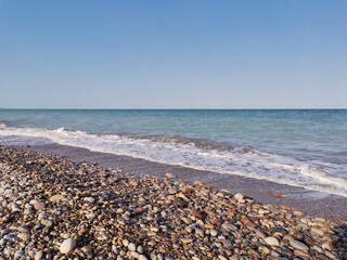 Fototapeta na wymiar Beach of foam stones and turquoise sea