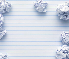 School supplies of blank lined notebook paper surrounded by more trashed balled up paper. Studying or writing mistakes concept.