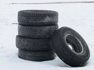 Stack of used tires with a wintry background.