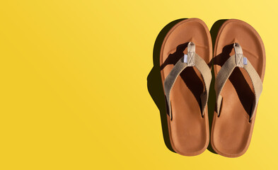 Flip flops isolated on yellow background. Top view and copy space. Slippers brown