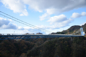 Fototapeta na wymiar 青空と山々に囲まれた大自然のなかに架かる吊橋