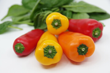 Small sweet peppers and spinach leaves isolated on a white background. Paprika
