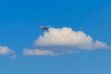 Naklejka na ściany i meble Flying orange helicopter in blue sky