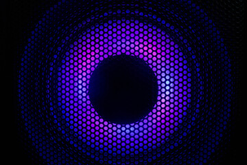 Close up photograph of a black speaker or sound system with purple led lighting.