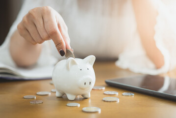 Obraz na płótnie Canvas Woman inserts a coin into a piggy bank, financial concept