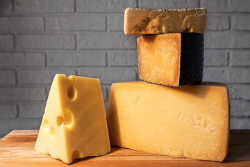 Pyramid of various cheeses on a wooden Board against a brick wall