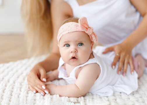 A Small Child Lies On The Floor Next To Mom